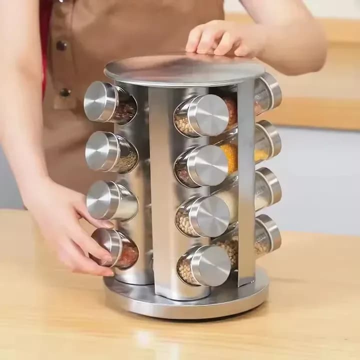rotating stainless steel spice rack with glass jars on a kitchen counter